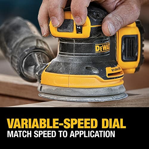 DeWalt variable-speed sander in use on wood.